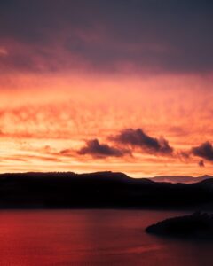 silhouette d'une montagne près d'un plan d'eau au coucher du soleil